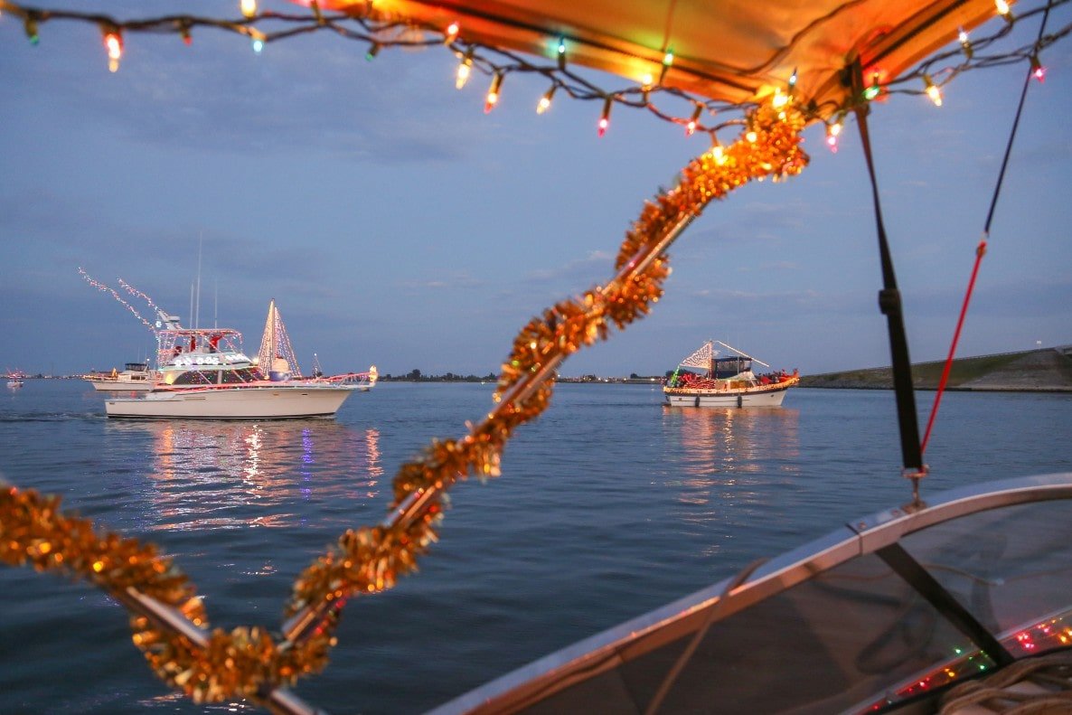 Boats on the water lit up in tinsel and lights for the Venice Christmas Boat Parade